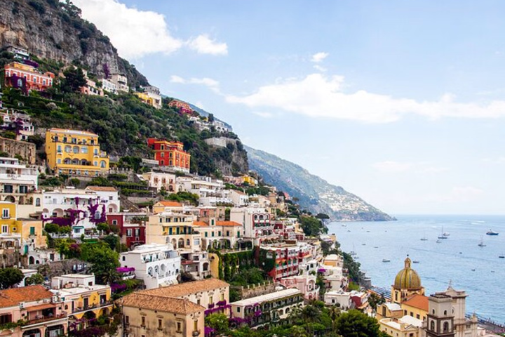 Colorful hillside buildings in Positano overlooking the sea with boats.