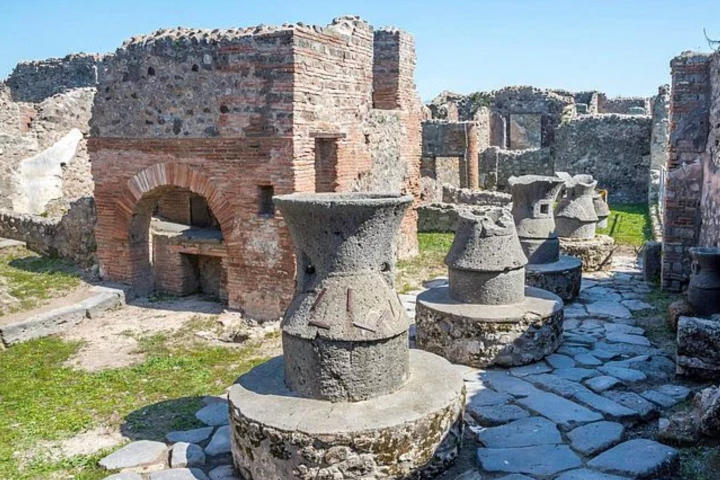Ancient stone mill and brick ruins under a clear blue sky.