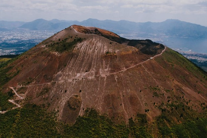 Aerial view of a volcanic mountain with a surrounding hiking trail.