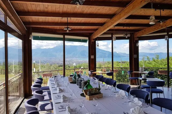 Dining area with large windows, mountain view, set tables, and wooden beams.