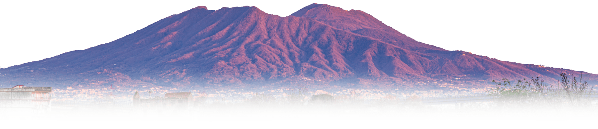 Mountains with purple hue above fog and cityscape.
